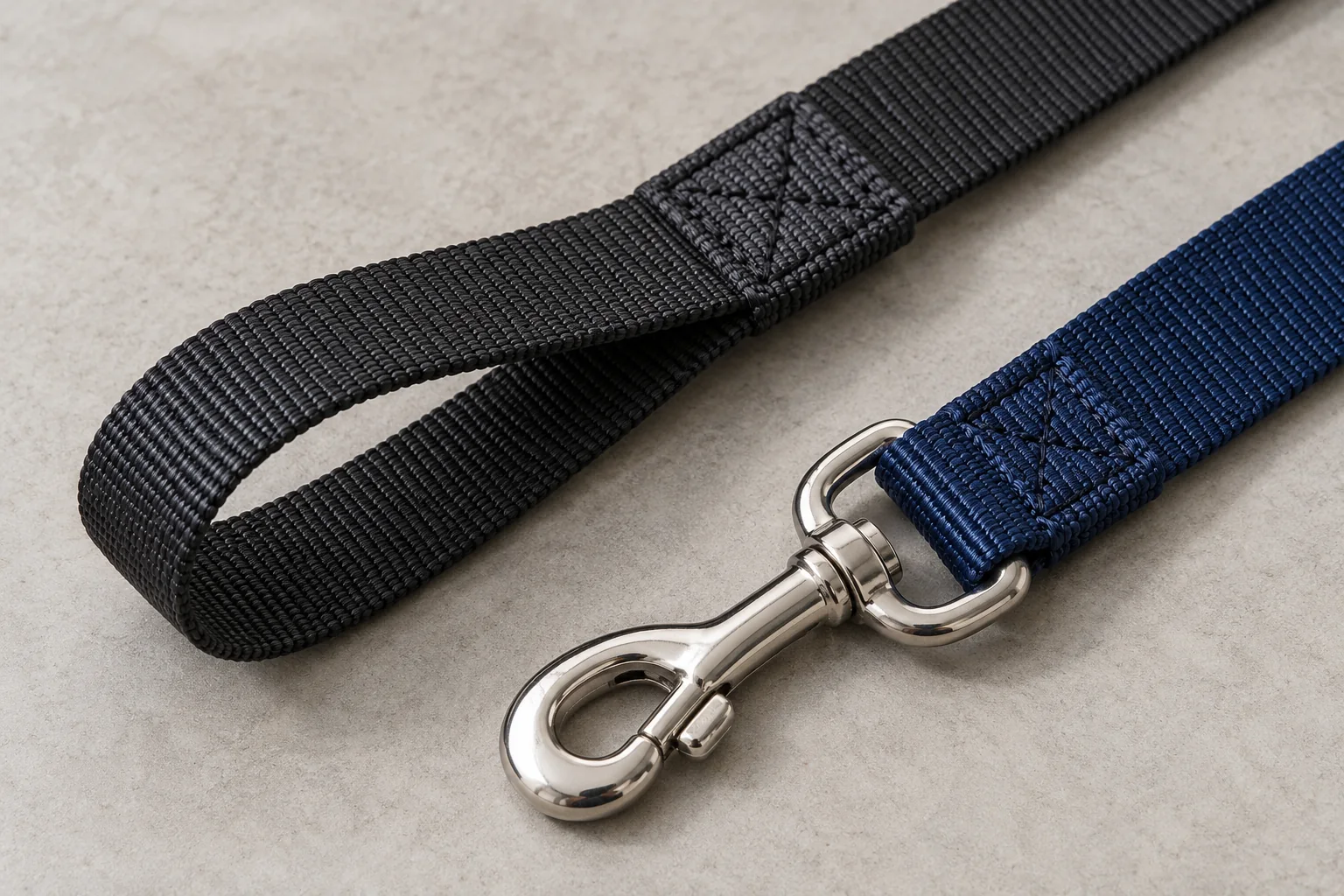 Close-up of folded nylon leash connections with rectangular stitching at a handle and snap hook.